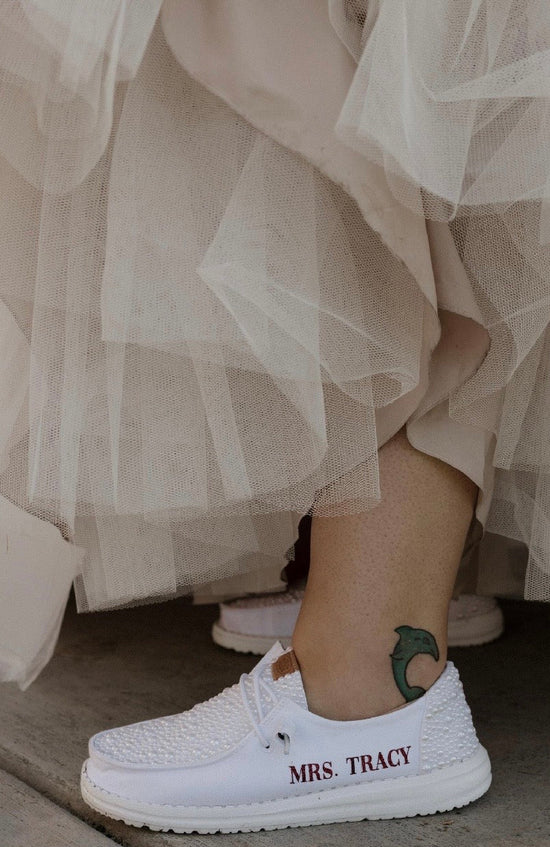 White sneakers with 'MRS. TRACY' text worn with a beige skirt.